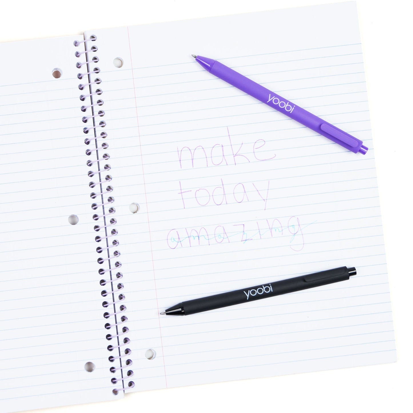 Inside of open one subject spiral notebook showing 3-ring hole punched perforated paper. Shown with pens