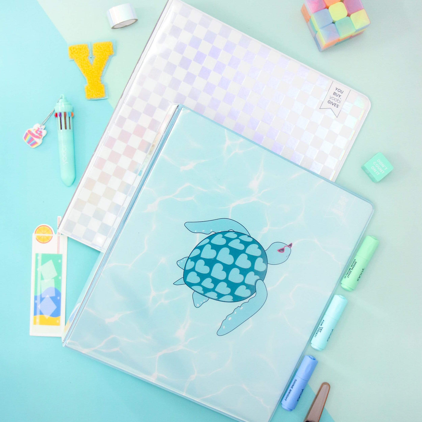 lifestyle image of turtle binder and holographic check binder with pen and markers
